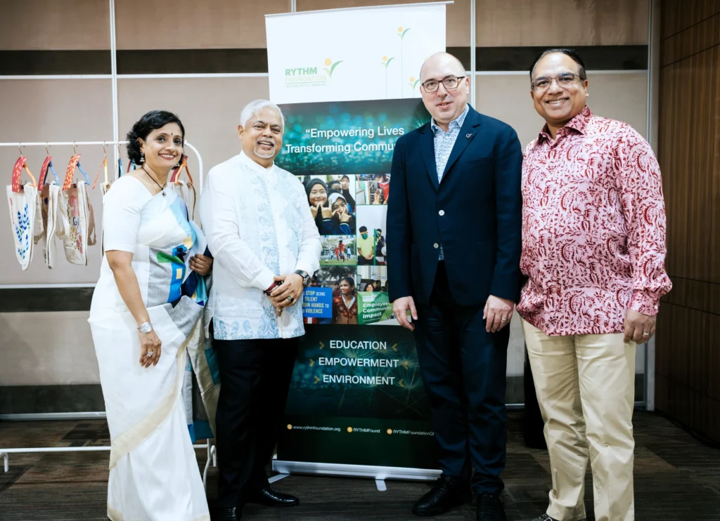 Datin Sri, Dato Sri, Mr JR Mayer and Mr Kuna Senathirajah at QI Group’s International Women’s Day 2026 event in front of the RYTHM Foundation display