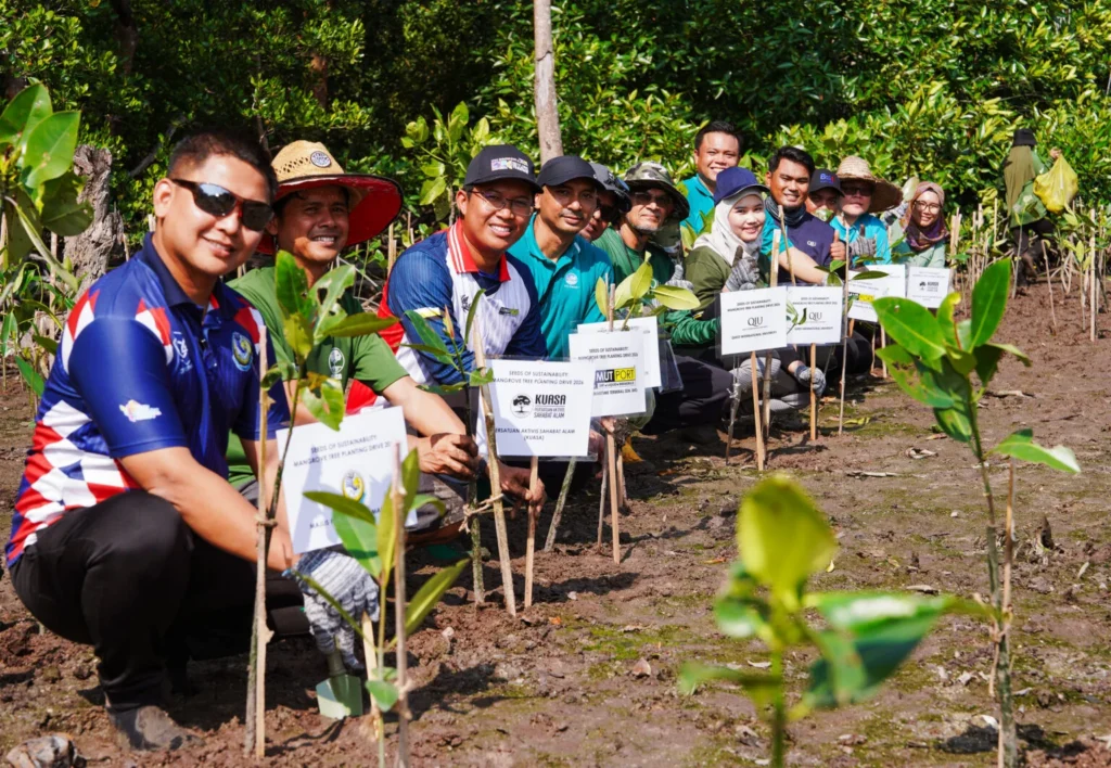 Participants showcasing the planted mangrove saplings together as part of a collective action on coastal conservation activity in Manjung.