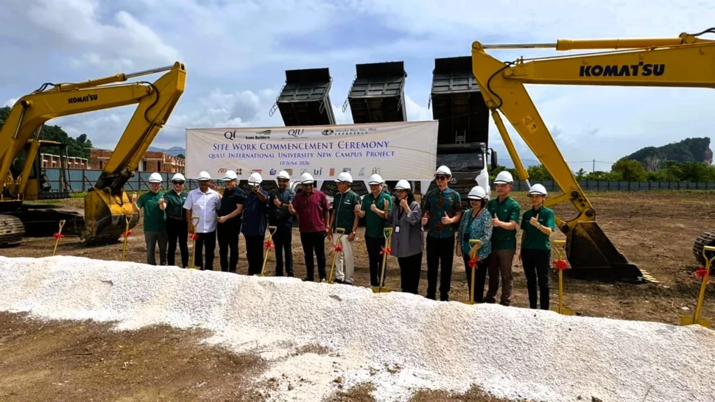 Participants gather at the project site flanked by construction equipment during the Site Work Commencement Ceremony for the new QIU campus.