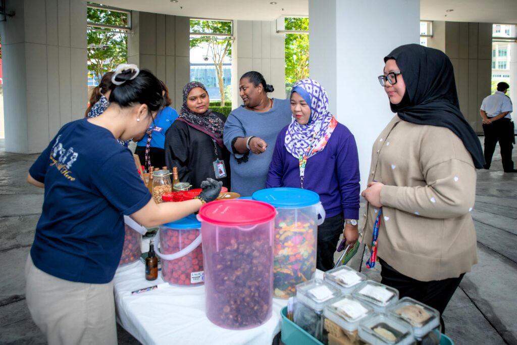 Employees browse refill products options at the Kita Refill mobile station during QI Group's Plastic Free July initiative.