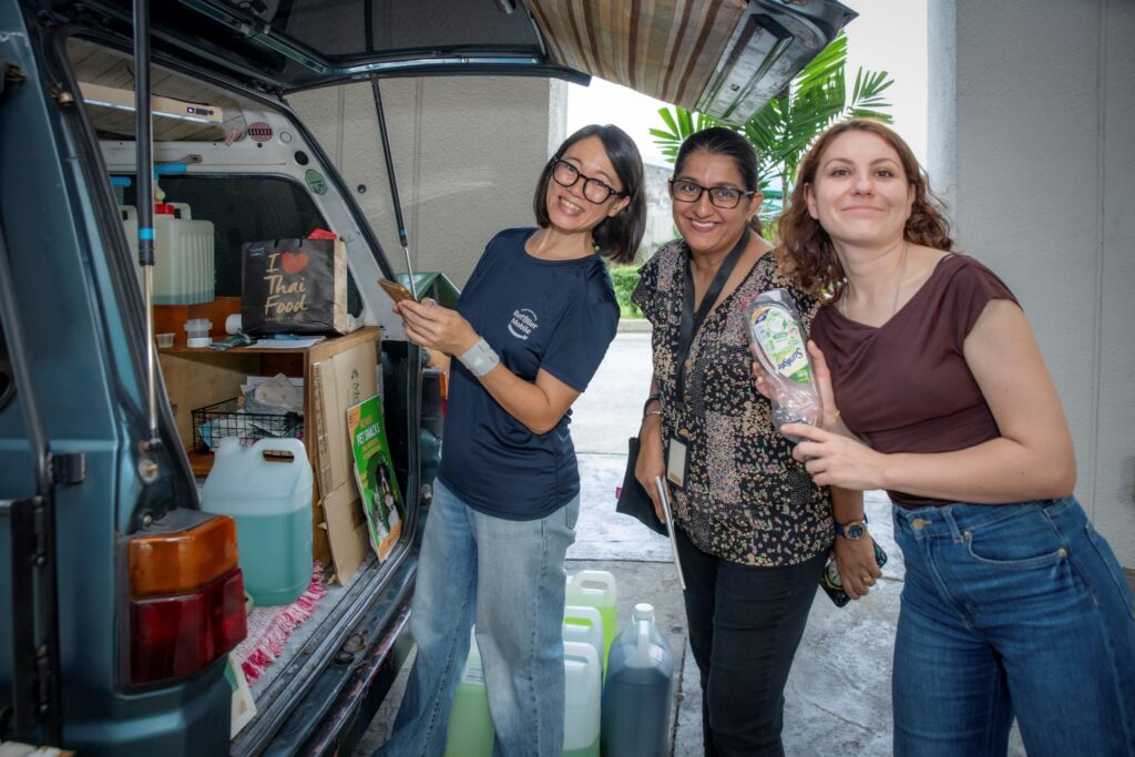 Employees refill reusable containers with household products at the Kita Refill mobile station during QI Group's Plastic Free July sustainability initiative.